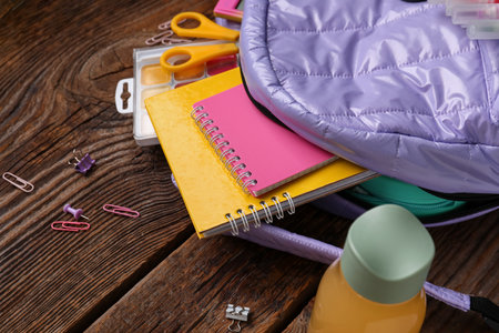 Lilac school backpack with bottle of juice and different stationery on wooden backgroundの写真素材