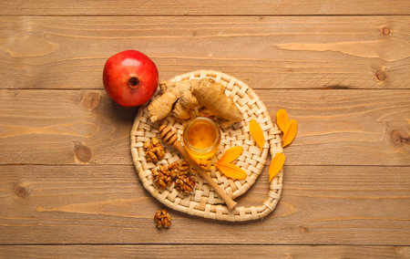 Jar of sweet honey with walnut, ginger and pomegranate on wooden backgroundの写真素材