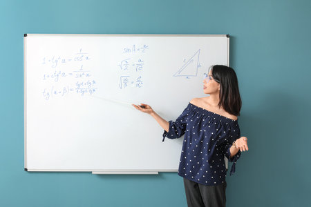 Asian Math teacher near flipboard in classroomの写真素材