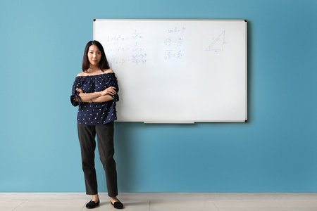 Asian Math teacher near flipboard in classroomの写真素材