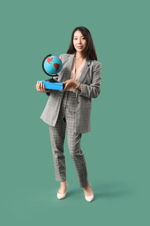 Asian Geography teacher with globe and books on green backgroundの写真素材