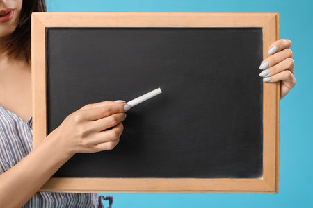 Female Asian teacher with chalkboard on blue background, closeupの写真素材