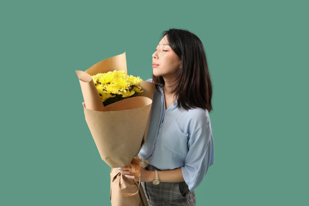 Female Asian teacher with bouquet of flowers on green backgroundの写真素材