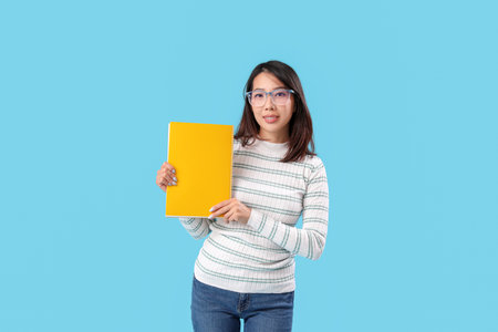 Female Asian teacher with notebook on blue backgroundの写真素材