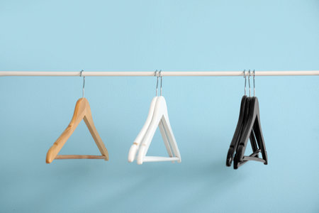 Rack with wooden clothes hangers on blue backgroundの写真素材