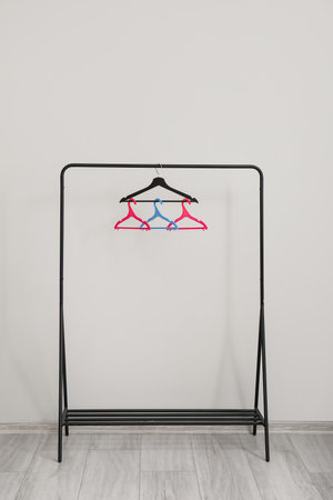 Rack with plastic clothes hangers near gray wallの写真素材