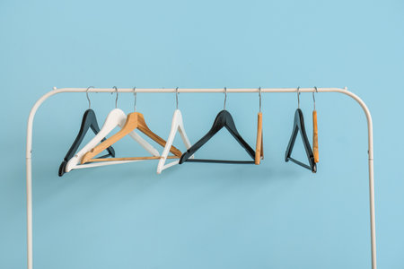 Rack with wooden clothes hangers on blue backgroundの写真素材
