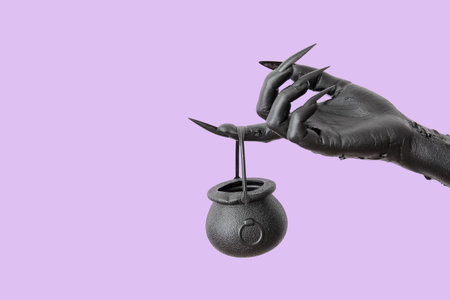 Black hand of witch and cauldron on purple background. halloween celebrationの写真素材