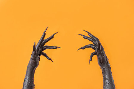 Black hands of witch on orange background. halloween celebrationの写真素材