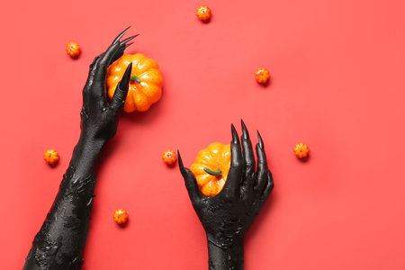 Black hands of witch with pumpkins on red background. halloween celebrationの写真素材