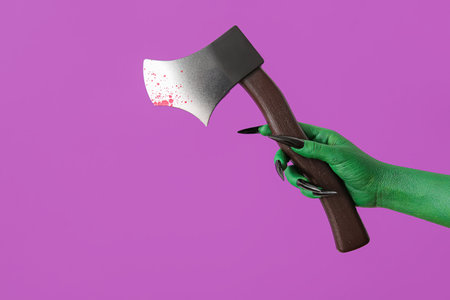 Green hand of witch with ax on purple background. halloween celebrationの写真素材