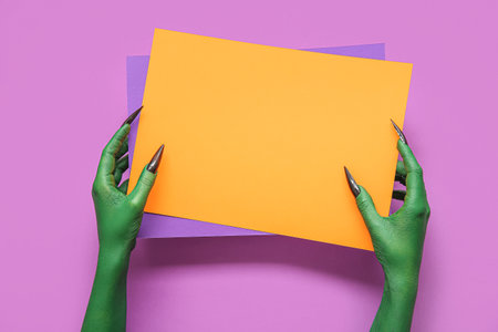 Green hands of witch with blank paper sheets on purple background. halloween celebrationの写真素材