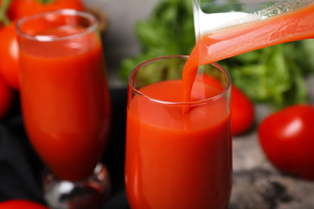 Pouring of tasty tomato juice into glasses, closeupの写真素材