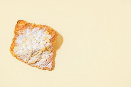 Sweet croissant with powdered sugar and nuts on beige backgroundの写真素材
