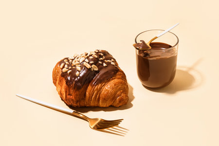 Sweet croissant and glass of chocolate on beige backgroundの写真素材