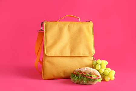 Lunch box bag with sandwich and grapes on pink backgroundの写真素材