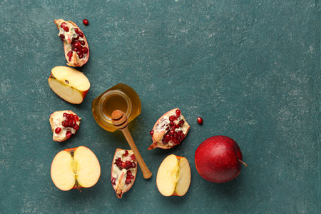 Jar of honey with pomegranate and apples for Rosh Hashanah celebration (Jewish New Year) on blue backgroundの写真素材