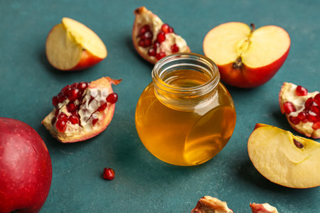 Jar of honey with pomegranate and apples for Rosh Hashanah celebration (Jewish New Year) on blue backgroundの写真素材