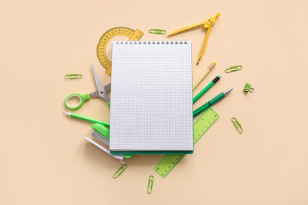 Composition with blank notebook and different school stationery on beige background