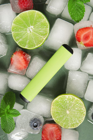 Electronic cigarette with lime, berries and ice cubes on green backgroundの写真素材