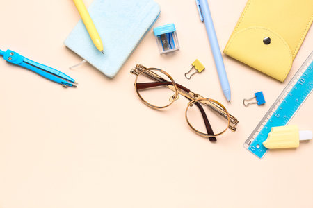 Stylish eyeglasses with stationery supplies on pink background