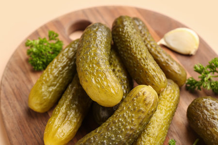 Wooden board with pickled cucumbers, parsley and garlic on orange backgroundの写真素材