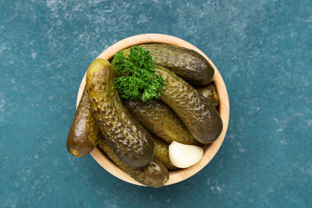 Wooden bowl with pickled cucumbers, parsley and garlic on blue backgroundの写真素材