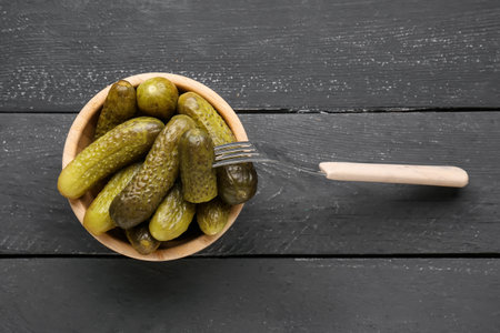 Bowl with pickled cucumbers on black wooden backgroundの写真素材