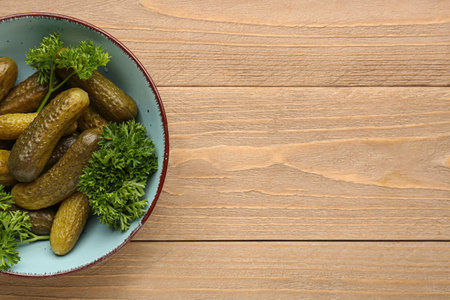 Bowl with pickled cucumbers and parsley on wooden backgroundの写真素材