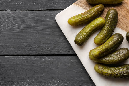 Board with pickled cucumbers on black wooden backgroundの写真素材