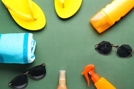 Frame made of beach accessories and sunscreen cream on green backgroundの写真素材