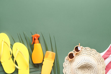 Set of beach accessories, sunscreen cream and palm leaf on green backgroundの写真素材