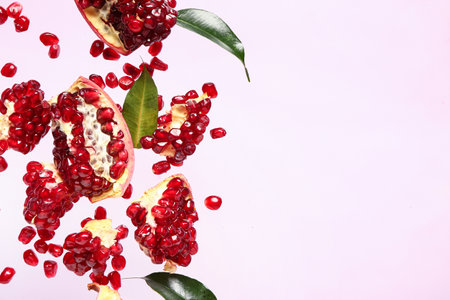 Flying fresh pomegranates with seeds and leaves on lilac backgroundの写真素材