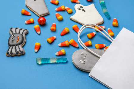 Shopping bag with tasty candy corns and cookies for Halloween on blue backgroundの写真素材