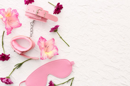 Composition with beautiful flowers and sex toys on white background