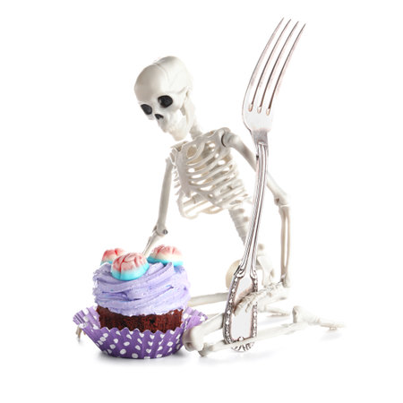 Delicious Halloween cupcake with candies and skeleton on white backgroundの写真素材