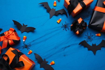 Composition with gift boxes, tasty candy corns and paper bats for Halloween on blue backgroundの写真素材