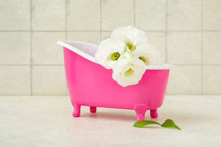 Small bathtub and beautiful eustoma flowers on light tableの写真素材