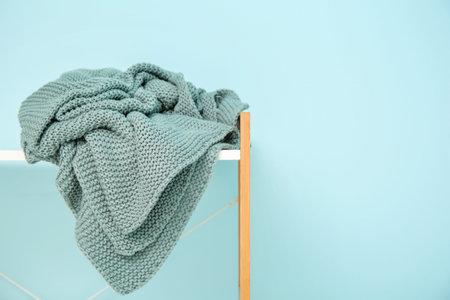 Shelving unit with cozy blanket near blue wall, closeup