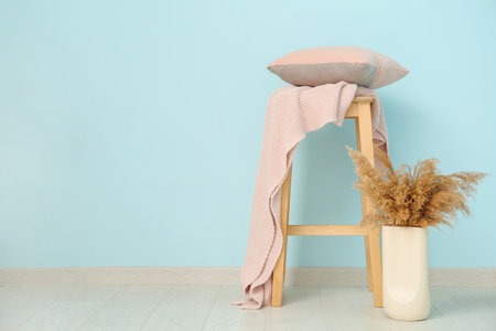 Stool with blanket and cushion near blue wallの写真素材