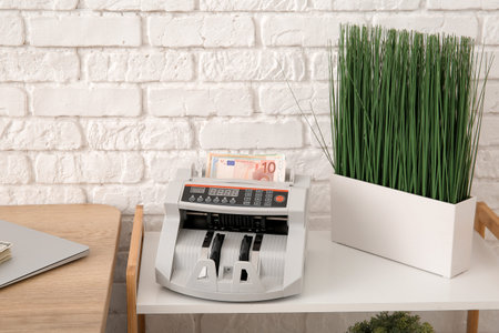 Cash counting machine with euro banknotes on shelf in officeの写真素材