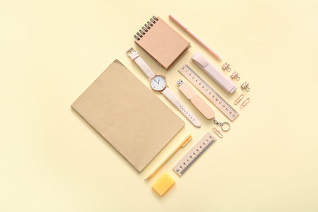 Different school stationery, notebooks and wristwatch on beige backgroundの写真素材