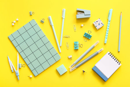 Different school stationery and notebooks on yellow background