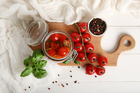 Jar with canned tomatoes and basil on white wooden tableの写真素材