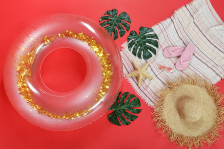Inflatable ring with beach accessories on red backgroundの写真素材
