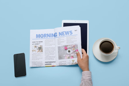 Woman reading newspaper with coffee and mobile phone on blue backgroundの写真素材