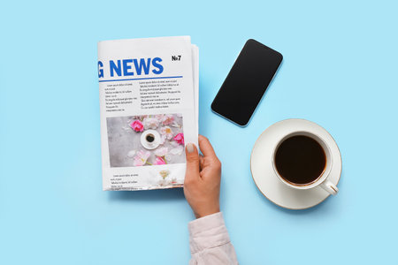 Woman reading newspaper with coffee and mobile phone on blue backgroundの写真素材
