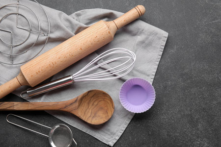 Set of different kitchen utensils with napkin on dark background