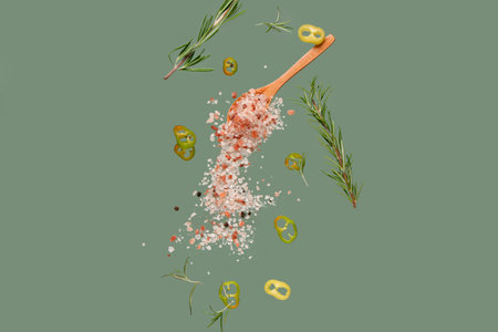 Flying salt, chili pepper and rosemary on green backgroundの写真素材