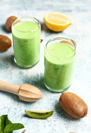 Glasses of fresh kiwi smoothie with mint and lemon on light blue backgroundの写真素材